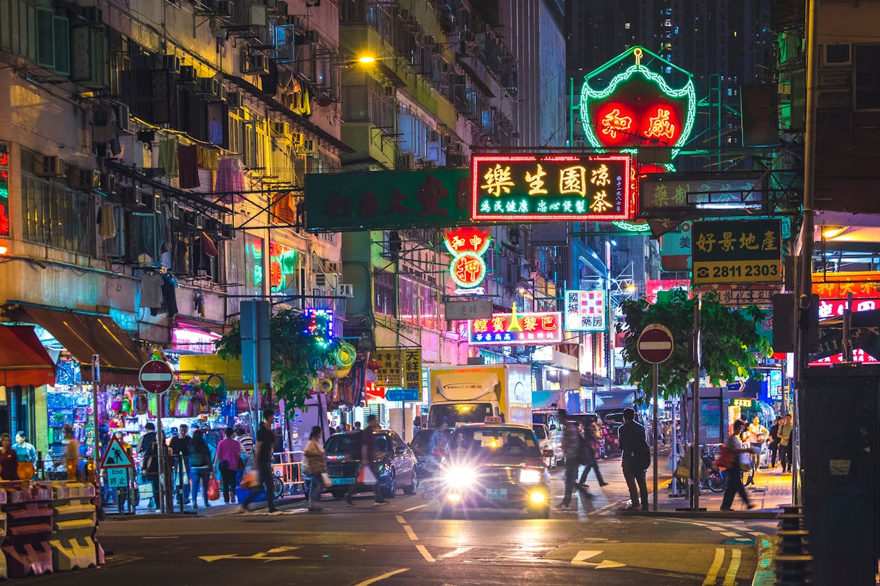 Colorful neon lights illuminate a bustling street in the New Territories, Hong Kong, by night.